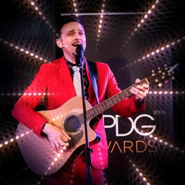 Milano performing in a red suit at the 2019 APDG Awards