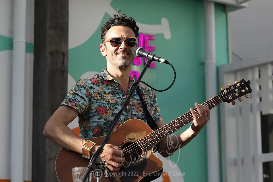 Milano smiling as he plays acoustic guitar at Republica, St Kilda